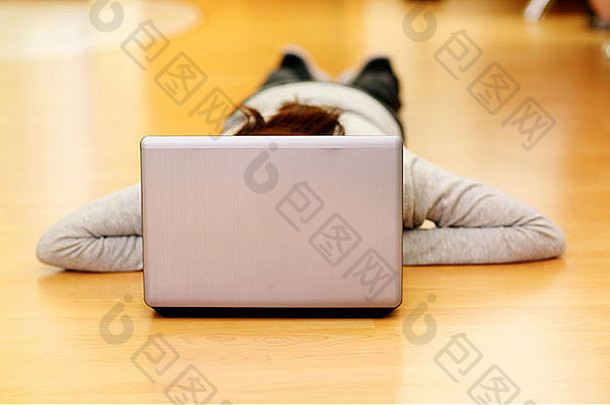 躺在地板上拿着笔记本电脑的年轻美女