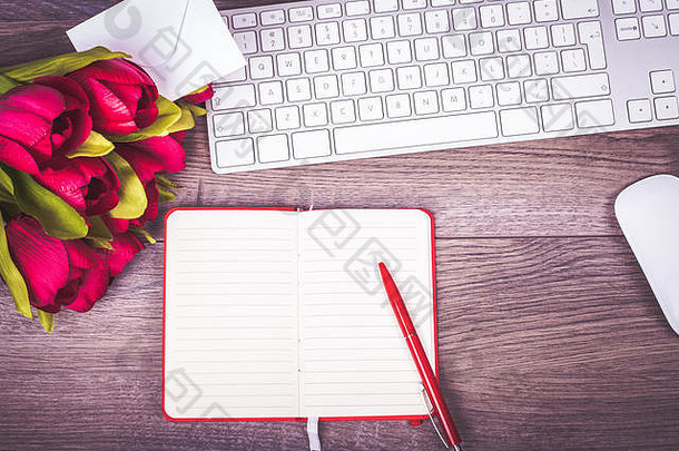 带键盘、鲜花和情书的办公桌。从上面看。拷贝空间