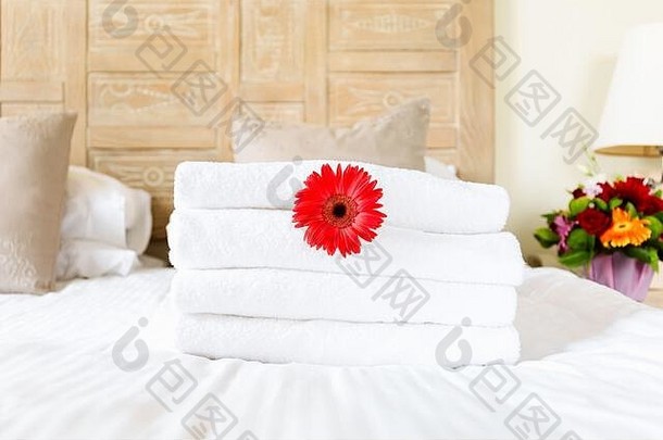 红色的花朵在新鲜的白色毛巾堆在<strong>高档酒</strong>店房间。独处、出游、休闲、数字排毒、旅行、度假等概念。水平的