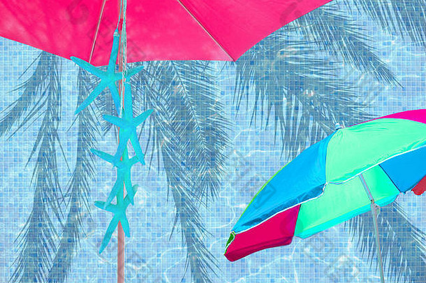粉红色的阳伞绿松石海星绿松石蓝色的池水表面背景