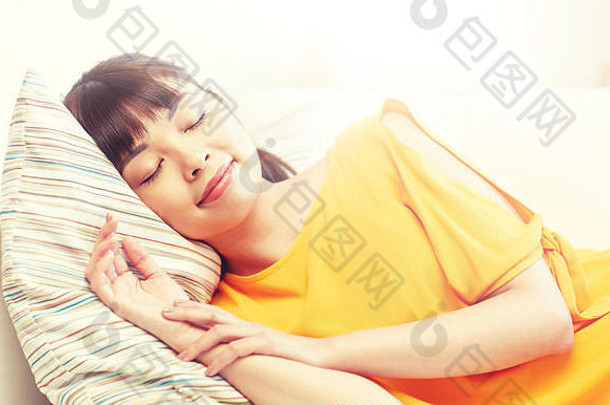 快乐的亚洲少女睡在家里的沙发上