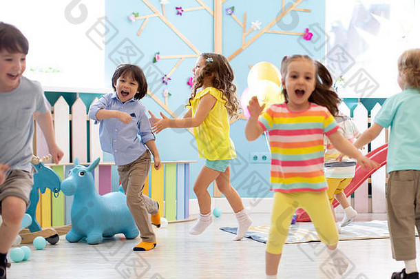 一群快乐的男孩和女孩的孩子在日托中心跑步。在幼儿园玩耍的孩子