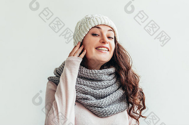 美丽的女人<strong>冬季</strong>肖像，真实的情感。留着长发的笑女孩，穿着<strong>保暖</strong>的衣服，戴着帽子，围巾，白色背景。年轻的时髦女孩看起来快乐、兴奋，玩得很开心
