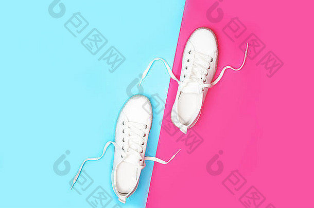 白色运动鞋位于明亮的霓虹色蓝粉色背景上。