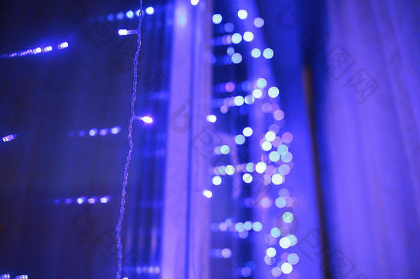 抽象模糊的蓝色和银色闪光灯泡背景：模糊的圣诞墙纸装饰概念。圣诞节节日背景：闪亮的圆形灯光庆典展示。