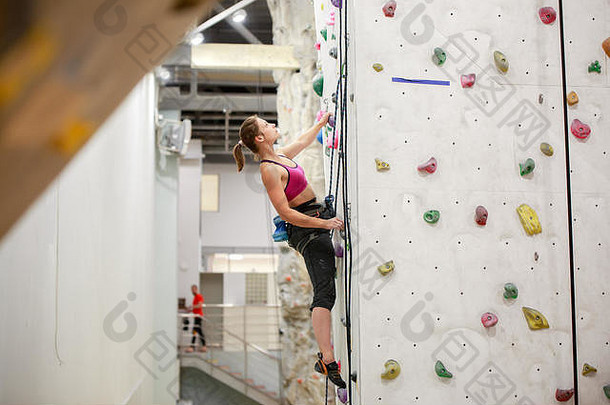 照片年轻的运动员锻炼<strong>墙</strong>岩石攀爬