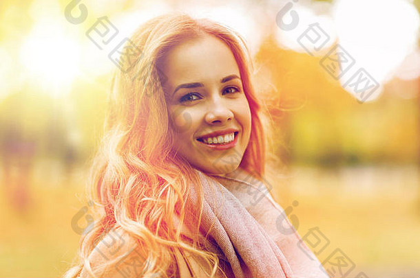 美丽快乐的年轻女子在秋天公园微笑
