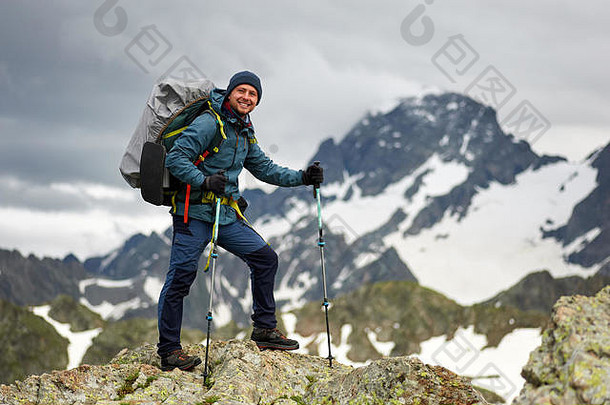 徒步旅行者站在山顶的悬崖上。男人有背包和登山杖。登山。拷贝空间