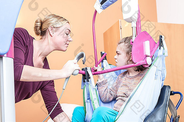 一个坐在轮椅上的<strong>残疾儿童</strong>，由一名志愿护理人员照料
