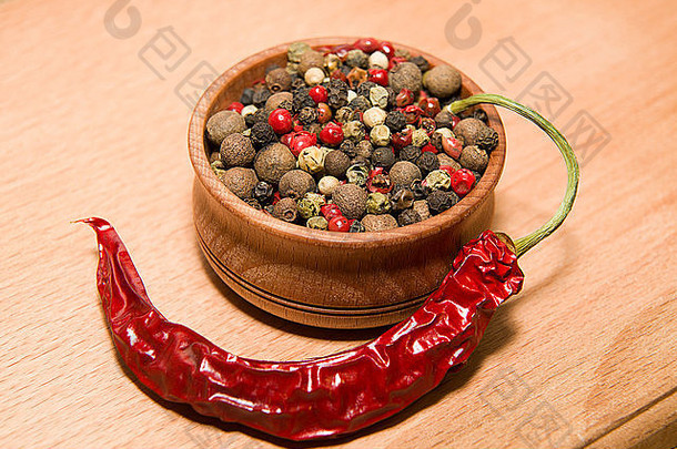 在木质表面上的胡椒和辣椒颗粒的混合物