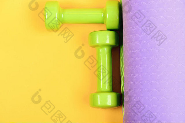 杠铃小大小瑜伽席关闭健康的形状体育运动概念哑铃使光绿色塑料黄色的紫色的背景前视图塑造健身设备