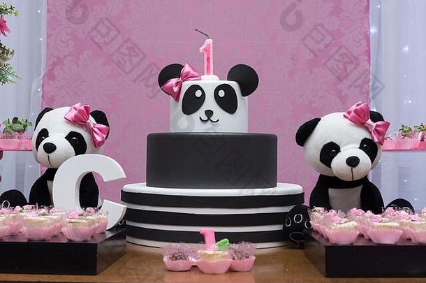 一桌糖果和生日蛋糕。以熊猫为主题的女孩派对——精致的粉色和白色装饰。一岁生日派对。