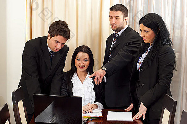 四位商务人士使用笔记本电脑在会议室进行讨论