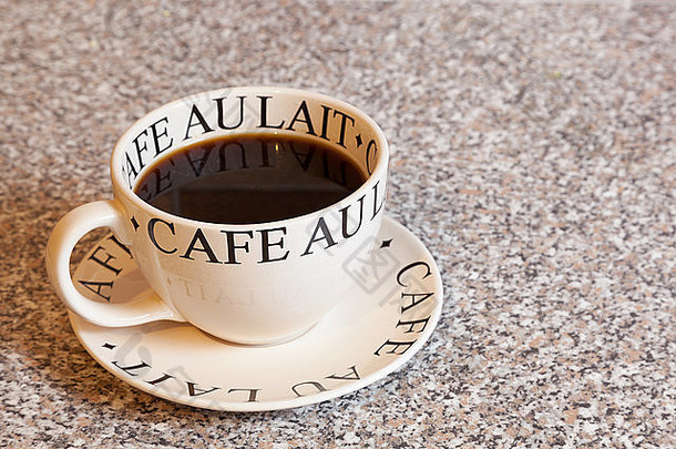 花岗岩台面上的配套茶碟上放着一大杯黑咖啡