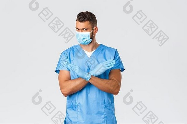 医疗工作者2019<strong>冠状病毒</strong>疾病<strong>病毒</strong>概念严肃的专业医生，穿着蓝色护甲和医用口罩的男护士告诉停止，显示