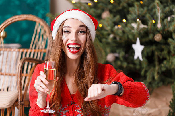 有吸引力的圣诞节女人穿圣诞老人他红色的毛衣坐着地板上舒适的一年云杉等待香槟一年一年圣诞节假期记忆礼物购物折扣商店雪少女圣诞老人老人化妆发型狂欢节