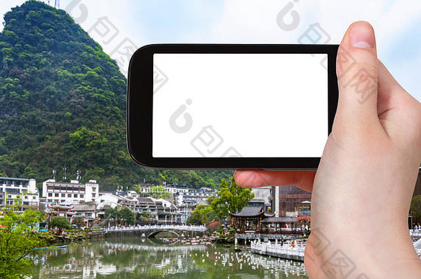 旅游理念——春季在智能手机上拍摄中国阳朔镇的旅游照片，手机屏幕上带有广告标识