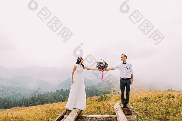 在木桥上手持花束的新婚夫妇。山中蜜月