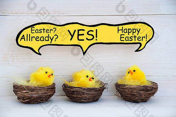 三只坐在<strong>复活节</strong>篮子里的<strong>复活节</strong>小鸡，或在白色木制背景上用黄色羽毛筑巢，并带有滑稽的演讲气球