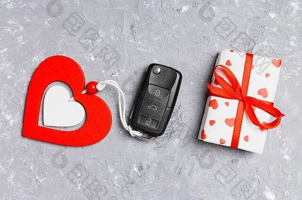 作为情人节礼物的车钥匙、礼品盒和心形的俯视图，背景为水泥。浪漫的概念。