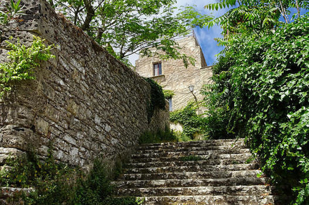 石头楼梯紧挨着一堵古老的石墙，通向一座正面为石头的房子