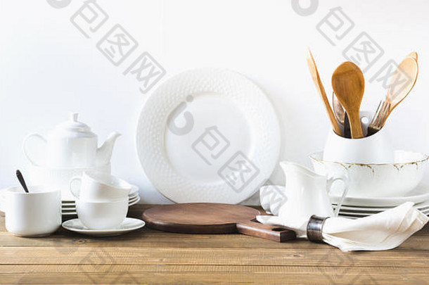 白色厨房用具、餐具和其他不同的白色材料，用于白色木板上。空间。