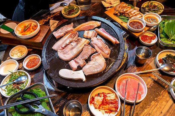 韩国餐厅的煎熟黑猪肉餐，新鲜美味的韩国美食，铁板上的生菜，特写，空间，生活方式