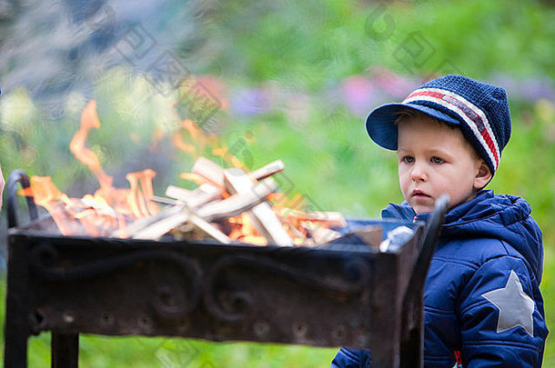 男孩看着老式的金属篝火准备烧烤