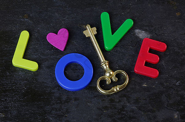 石板背景上的古董钥匙，字母中有“爱”一词