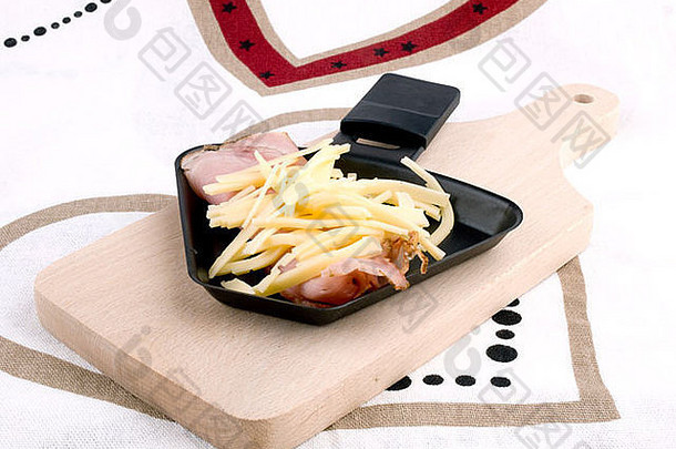 Raclette平底锅，案板上有edam奶酪和火腿