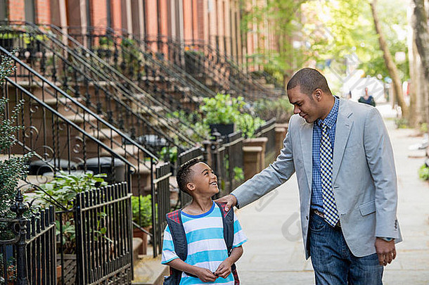 一个成年人和一个孩子，一对父子，一起走在城市的街道上。