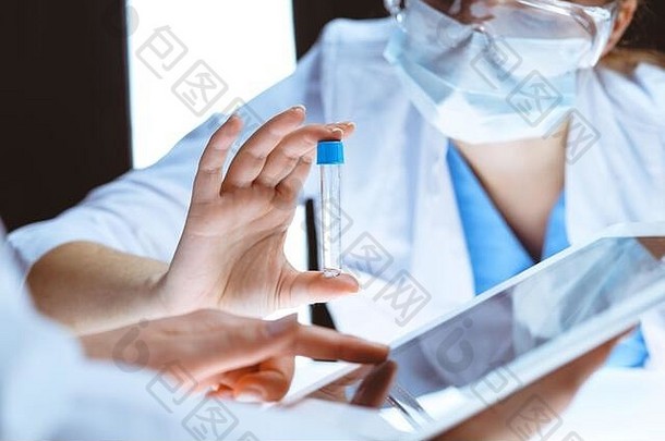 冠状病毒大流行。专业女科学家，戴防护眼镜，在实验室研究试管。医学与病毒防护的概念