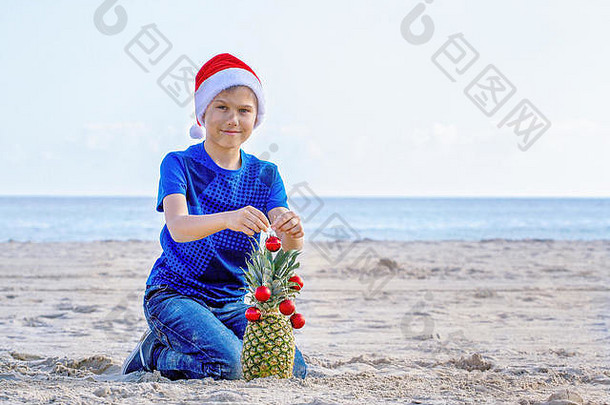 圣诞节假期男孩红色的圣诞老人他装修菠萝圣诞节树阳光明媚的桑迪海滩海