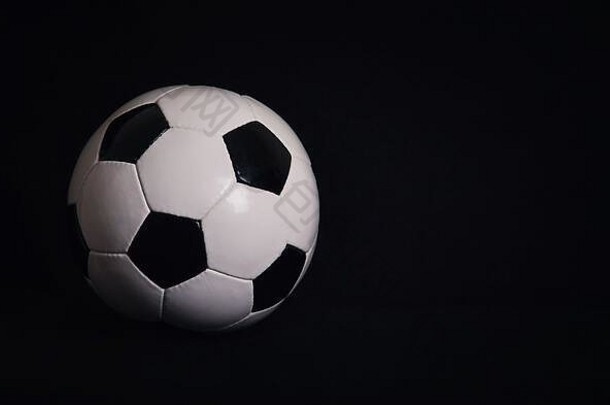 在黑色背景上隔离的经典足球，带有用于<strong>宣传</strong>和广告的空间。真实照片，da上方的传统足球符号