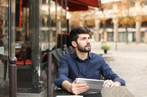 一名心怀不满的男子在街边咖啡馆用平板电脑玩网络游戏。