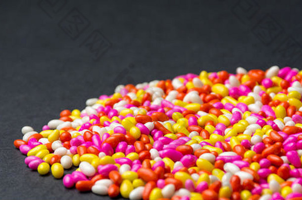 色彩斑斓的甜蜜的糖果背景多颜色巧克力模式孤立的黑色的背景色彩斑斓的壁纸