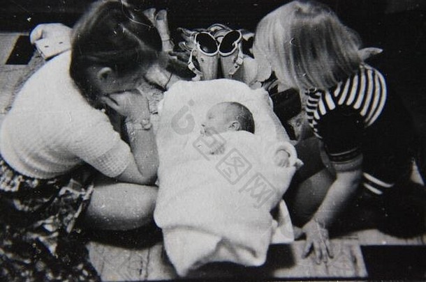 精美的70年代复古黑白极端照片，三个兄弟姐妹第一次见面，包括一个新生儿。