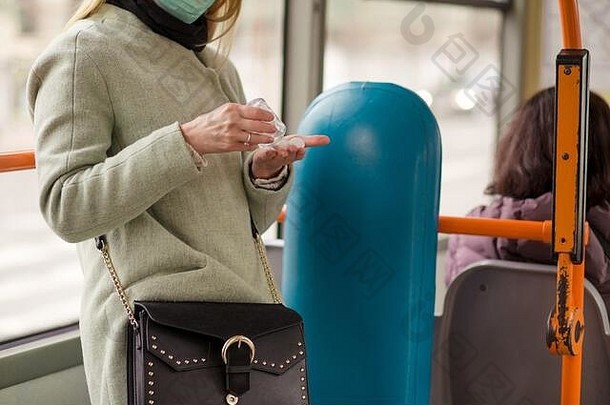 在欧洲城市的<strong>公交车上</strong>，一名妇女站在路上使用洗手液凝胶