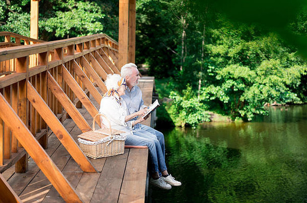 年老的妻子和丈夫坐在篮子附近的木桥上