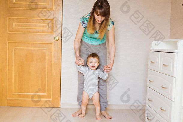 妈妈教她可爱的小儿子手牵着手走路身体部分第一步婴儿步概念