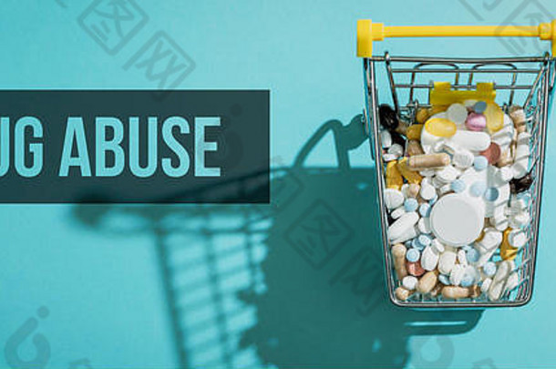 装满药丸、药片和胶囊的微型购物车：药店购物、药物和药物滥用概念