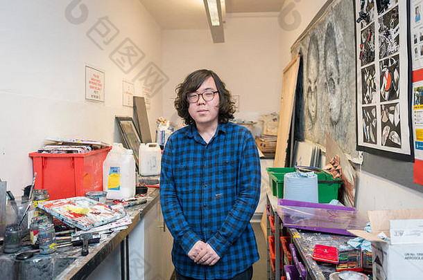 在一所大学的美术教室里，一名国际学生站在美术展览旁边
