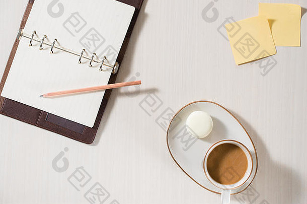 干净的笔记本，一杯咖啡和彩色的macaron放在灰色的桌面上。舒适的早餐。时尚平铺。甜杏仁饼。