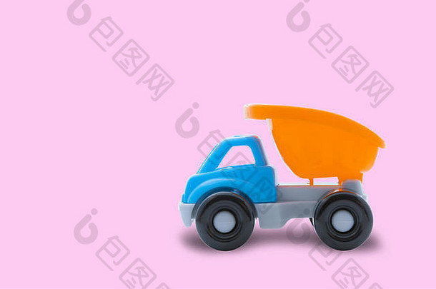 粉色背景上的玩具卡车、特写镜头、建筑作品或儿童游戏的概念