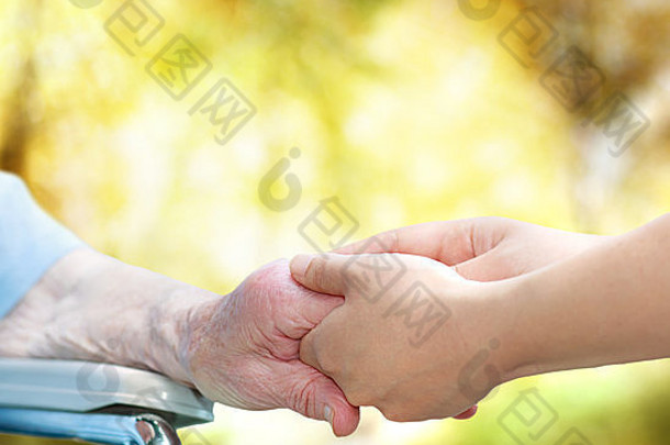 秋天，坐在轮椅上的老妇人与年轻的看门人手牵手