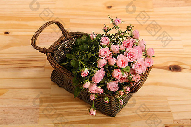 木桌上方的篮子里放着一束粉红色的小玫瑰。