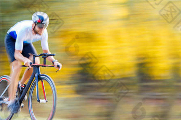 运动员在秋季公园骑自行车的镜头。运动速度循环模糊背景
