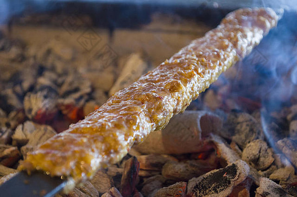 在餐厅风格的烤架上烹调阿达纳烤肉串，从中冒出的烟可能是