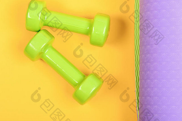 塑造健身设备杠铃小大小瑜伽席关闭健康的形状体育运动概念哑铃使光绿色塑料黄色的紫色的背景前视图