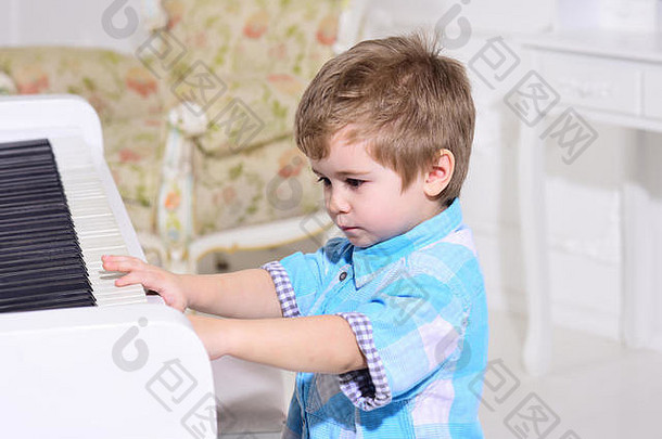 孩子坐计划键盘白色背景孩子花休闲音乐的仪器男孩可爱的可爱的把手指键盘计划